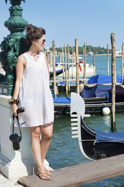 красивая молодая туристка наслаждается венецианским видом с гондолами, плавающими в голубом море
 - Фото, изображение