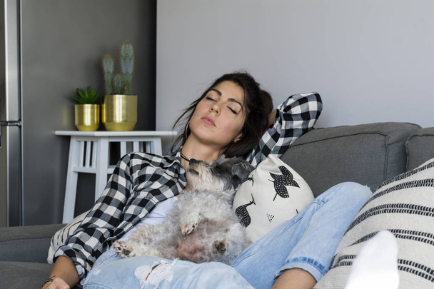Beautiful brunette girl sleeping with  her cute dog on a couch in a living room - Fotoğraf, Görsel