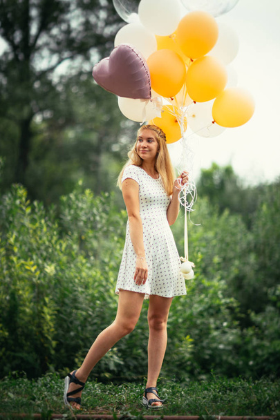 Nuori tyttö ilmapalloja luonnon taustalla
. - Valokuva, kuva