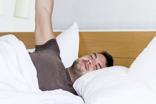 Man with raised arm in bed at home - Foto, imagen