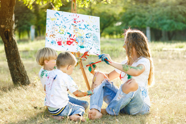 Una famiglia felice. Giovane madre carina divertirsi con i suoi figli all'aperto. Pittura di famiglia
 - Foto, immagini