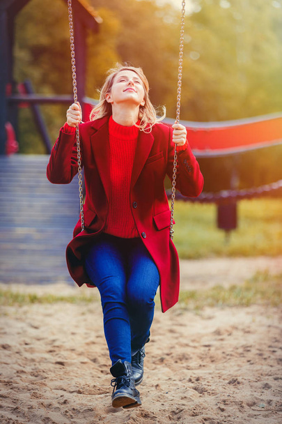 Νεαρό κορίτσι έχουν μια διασκέδαση στην κούνια του παιδιού σε παιδική χαρά στο πάρκο φθινόπωρο. - Φωτογραφία, εικόνα