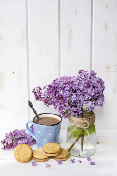 cup of coffee with milk and bouquet of lilac on white  wooden background - Valokuva, kuva