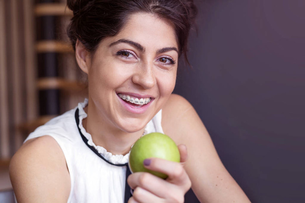 Portrait of a beautiful woman with braces on teeth and apple . Orthodontic Treatment. Dental care Concept - Fotoğraf, Görsel