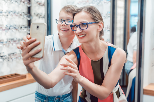Madre e figlio scattare selfie con nuovi occhiali al negozio di optometristi
 - Foto, immagini