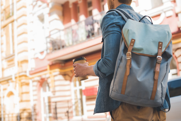 cropped shot of young man with backpack and coffee to go walking by street - Photo, Image
