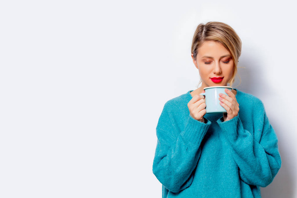 Portret pięknej białej kobiety uśmiechający się w niebieski sweter filiżankę kawy na białym tle, na białym tle. - Zdjęcie, obraz