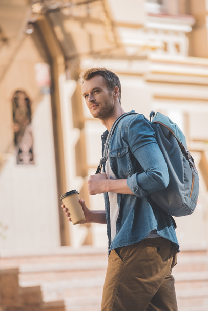 happy young man with coffee to go and backpack walking by city - Фото, изображение