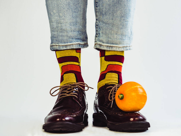 Beautiful pumpkins, men's legs in stylish, vintage shoes and bright, multi-colored socks. White background, isolated, close-up. Holidays, fashion, elegance - Foto, Imagem