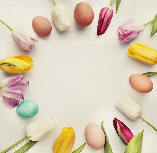 vista superior de coloridos huevos de Pascua y tulipanes haciendo marco con espacio de copia
 - Foto, imagen