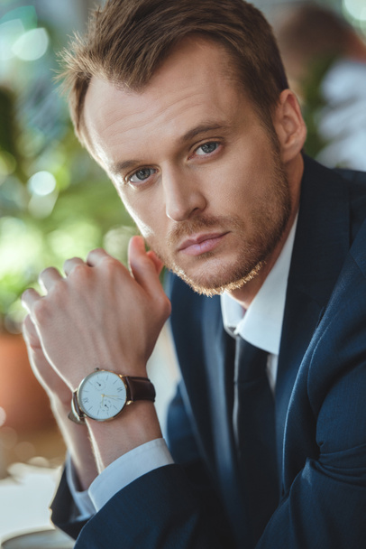 portrait of businessman with watch on wrist looking at camera in coffee shop - Photo, Image