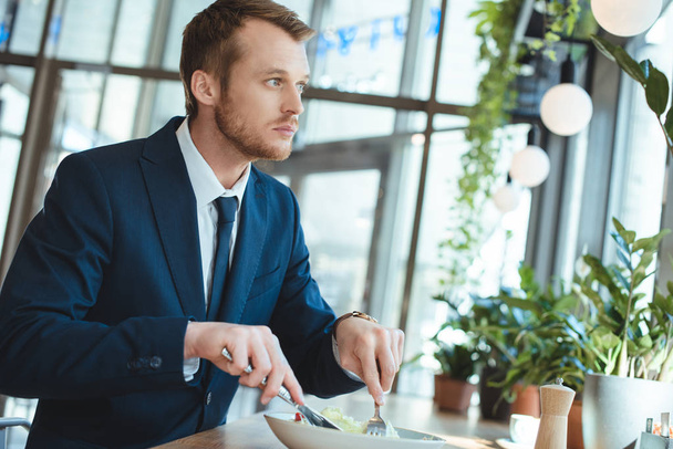 boční pohled zamyšlený podnikatel v uhýbaje obleku při obědě v kavárně - Fotografie, Obrázek