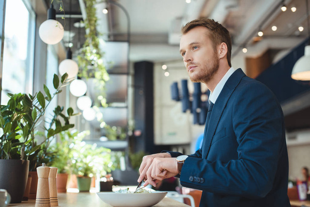 side view of thoughtful businessman looking away while having lunch in cafe - Photo, Image