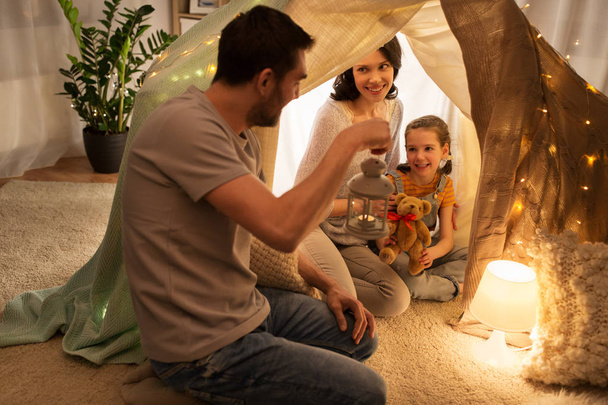happy family playing in kids tent at night at home - Foto, afbeelding