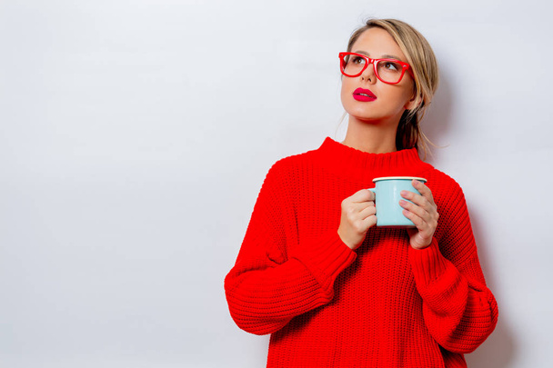 Portrait d'une belle femme blanche en pull rouge avec une tasse de café sur fond blanc, isolée
. - Photo, image