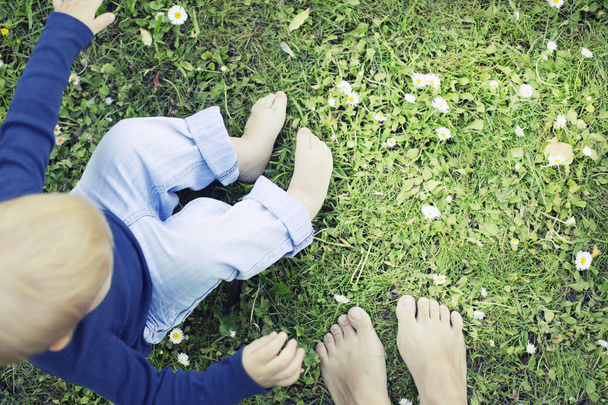 cropped image of mother and son enjoying nature while sitting on grass - Foto, Bild