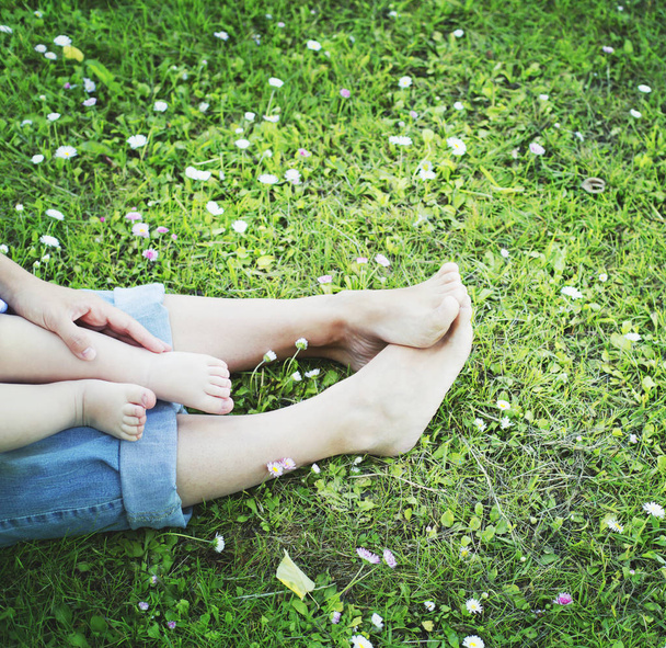 cropped image of mother and son enjoying nature while sitting on grass - Foto, afbeelding
