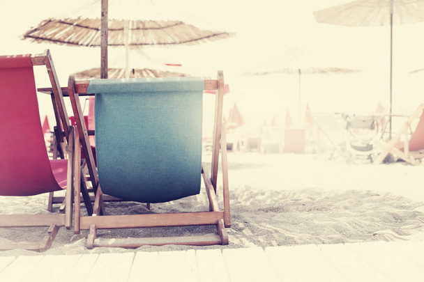 beach background with multicolored deck chairs and umbrellas near sea - Фото, зображення