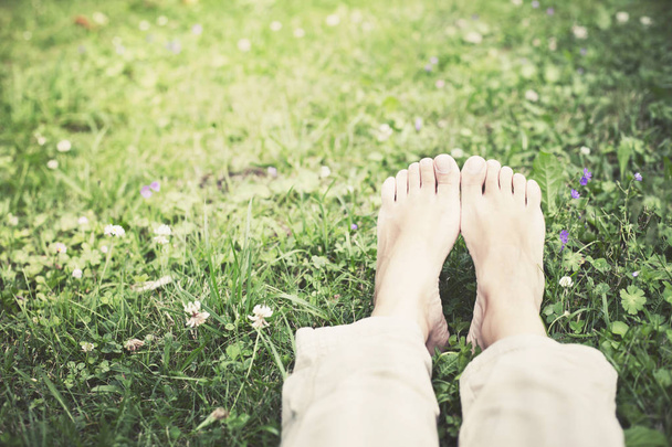 Feet in grass on meadow with daisy flowers - Foto, Imagen