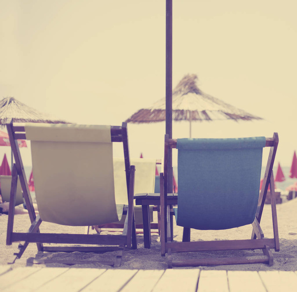 beach background with multicolored deck chairs and umbrellas near sea - Foto, Imagen