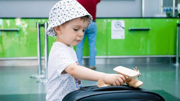 Portrait of little toddler boy with toy wooden airplane in international airport - Fotoğraf, Görsel