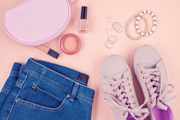 Blog de moda o concepto de revista. Zapatillas femeninas rosadas, jeans y maquillaje sobre fondo rosa pastel. Piso laico, vista superior mínimo fondo
. - Foto, imagen