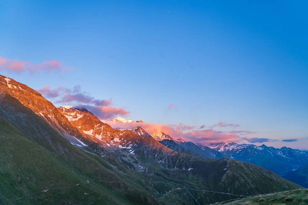 Scenic view of beautiful landscape of Swiss Alps in a Val De Bagnes area. Dramatic sunset scene in high mountains. Clouds covering high peaks of Valais Alps (Pennine Alps), Switzerland in a evening light. - Foto, Imagen