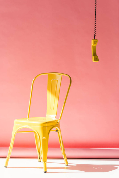 gele stoel en telefoon buis op roze - Foto, afbeelding