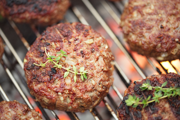 Харчове м'ясо - яловичі гамбургери на грилі барбекю барбекю з полум'ям
 - Фото, зображення
