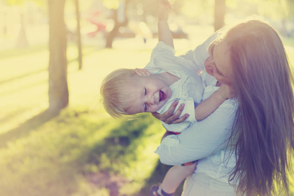 Szczęśliwy toddler chłopiec bawi się z matką w słoneczny park - Zdjęcie, obraz