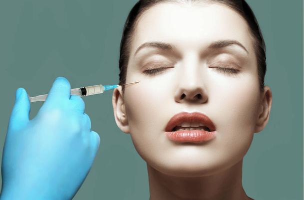 Frau bekommt kosmetische Botox-Injektion in Wange, Nahaufnahme. Frau im Schönheitssalon. Klinik für plastische Chirurgie - Foto, Bild