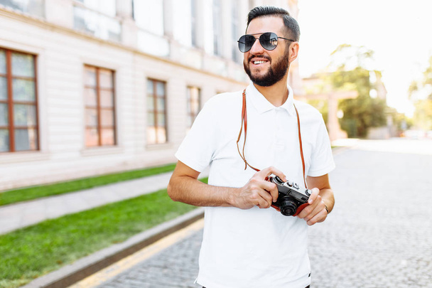 Stylish hipster with a beard and a camera, walking around the city with a camera in search of a frame - Фото, зображення
