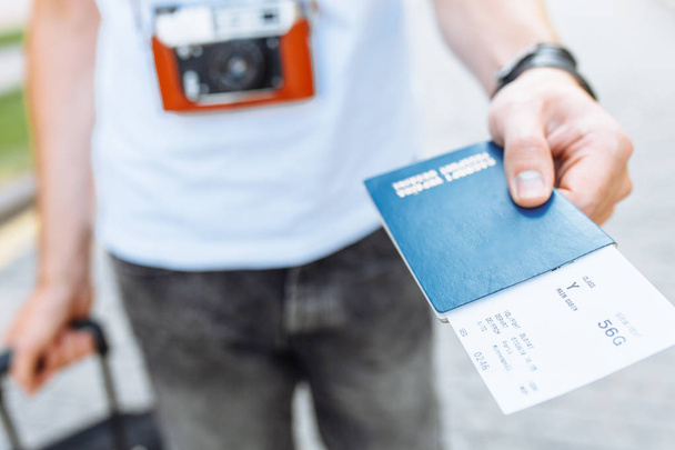 A man with a suitcase, holding a passport and tickets close-up - Fotoğraf, Görsel