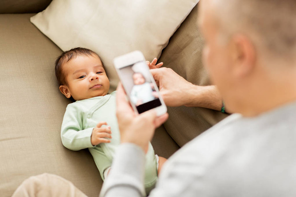 father photographing baby by smartphone - Фото, зображення