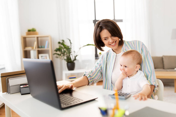 working mother with baby boy and laptop at home - Foto, afbeelding