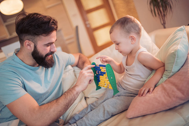 Vater und Kind spielen zu Hause gemeinsam mit Abakus - Foto, Bild
