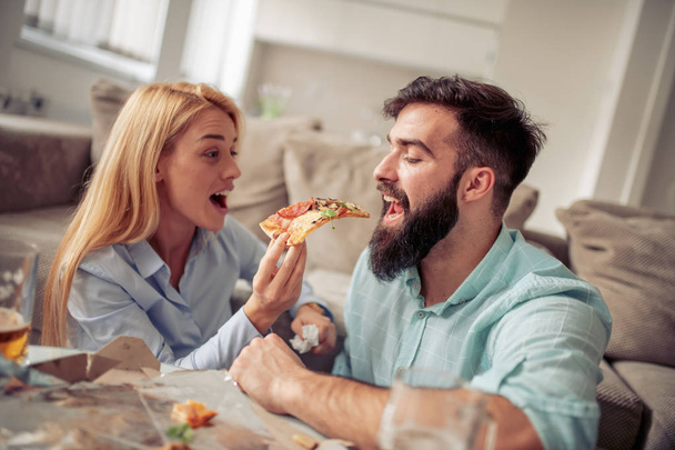 Couple eating pizza at home,enjoying together. - Foto, Imagen