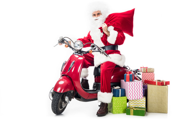 Weihnachtsmann im Kostüm hält Weihnachtssack in der Hand und sitzt auf Roller isoliert auf weißem Hintergrund  - Foto, Bild