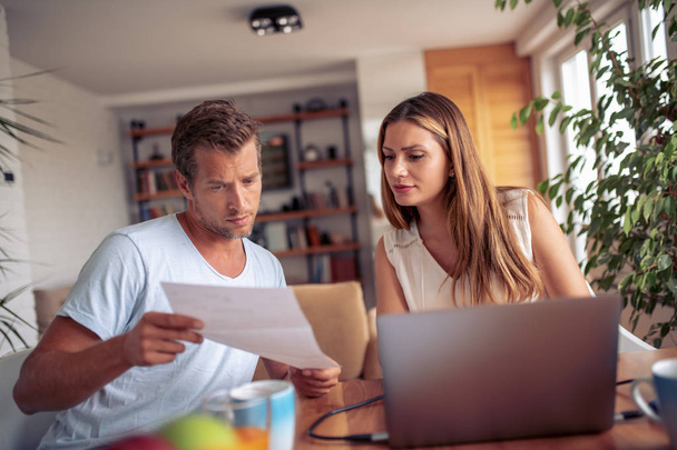 Jeune couple calculant leur budget domestique ensemble à la maison
. - Photo, image