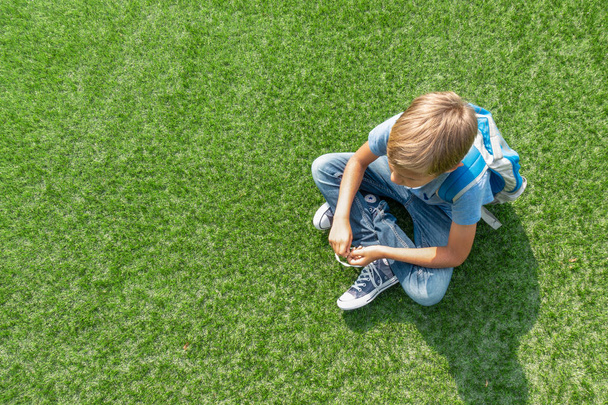 Malheureux triste garçon bouleversé assis seul sur l'herbe
 - Photo, image