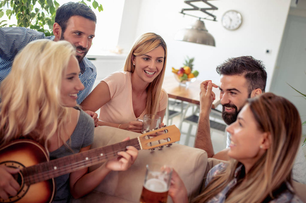 Des amis heureux jouent de la guitare et écoutent de la musique à la maison. - Photo, image