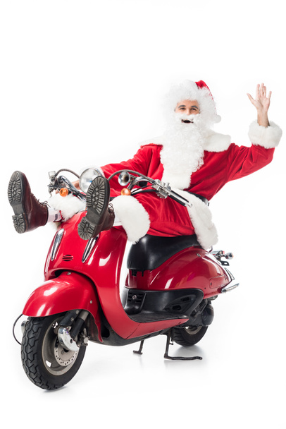 mutlu Noel Baba kostüm beyaz arka plan üzerinde izole scooter üzerinde el sallayarak  - Fotoğraf, Görsel