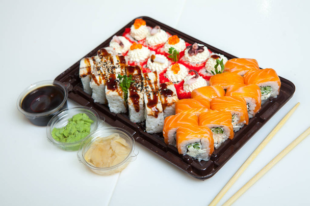 Japán ételtekercsek műanyag dobozban. Sushi beállítva egy műanyag csomag közelről elszigetelt fehér alapon. Sushi elvitelre vagy sushi szállításra. - Fotó, kép