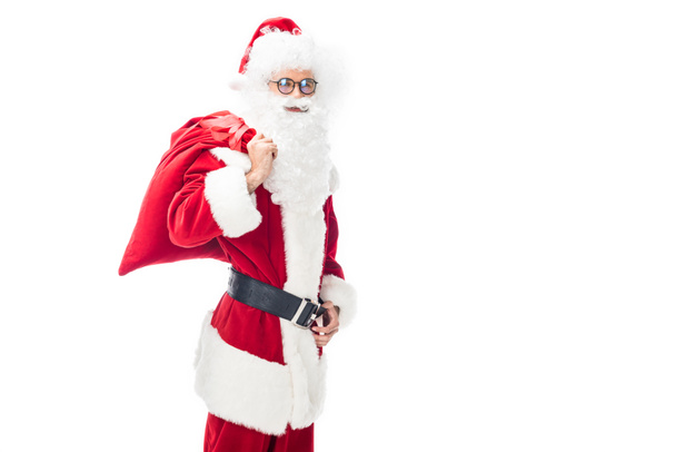 fröhliche Weihnachtsmann in Brille mit Weihnachtssack über der Schulter isoliert auf weißem Hintergrund  - Foto, Bild