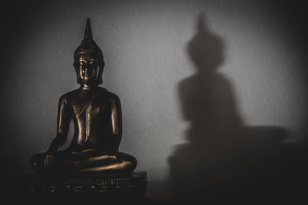 pacífico buddha flaco, estatua de budda proyectando una sombra en una pared
 - Foto, imagen