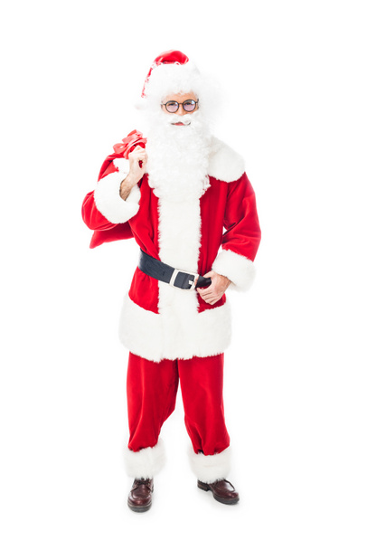 smiling santa claus in eyeglasses holding christmas sack over shoulder isolated on white background  - Foto, afbeelding