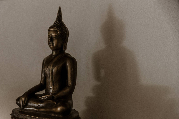 pacífico magrinho buddha, estátua de budda projetando uma sombra em uma parede
 - Foto, Imagem