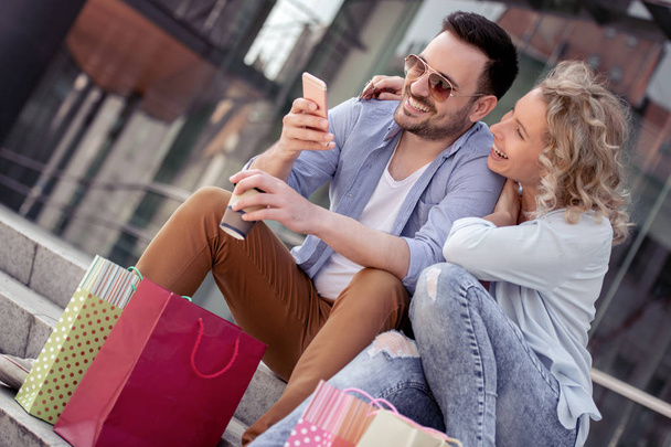 Fiatal pár, látszó-on smartphone a bevásárló túra a város - Fotó, kép