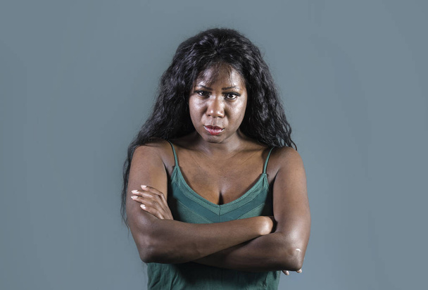 young beautiful and stressed black African American woman feeling upset and angry looking serious and pissed posing with folded arms on isolated studio background in moody face expression - Фото, изображение