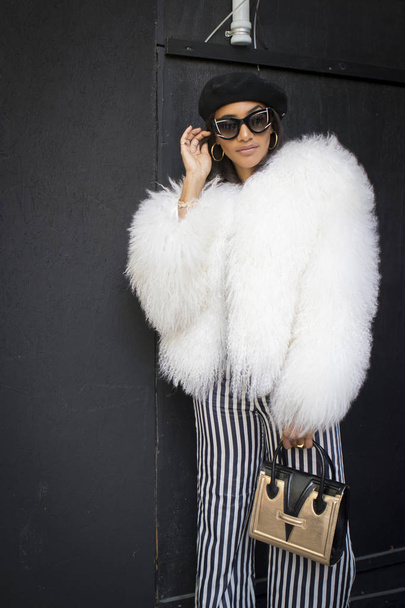 LONDON, United Kingdom- SEPTEMBER 14 2018: People on the street during the London Fashion Week. girl in a white fur coat, striped trousers and a black beret - Fotoğraf, Görsel